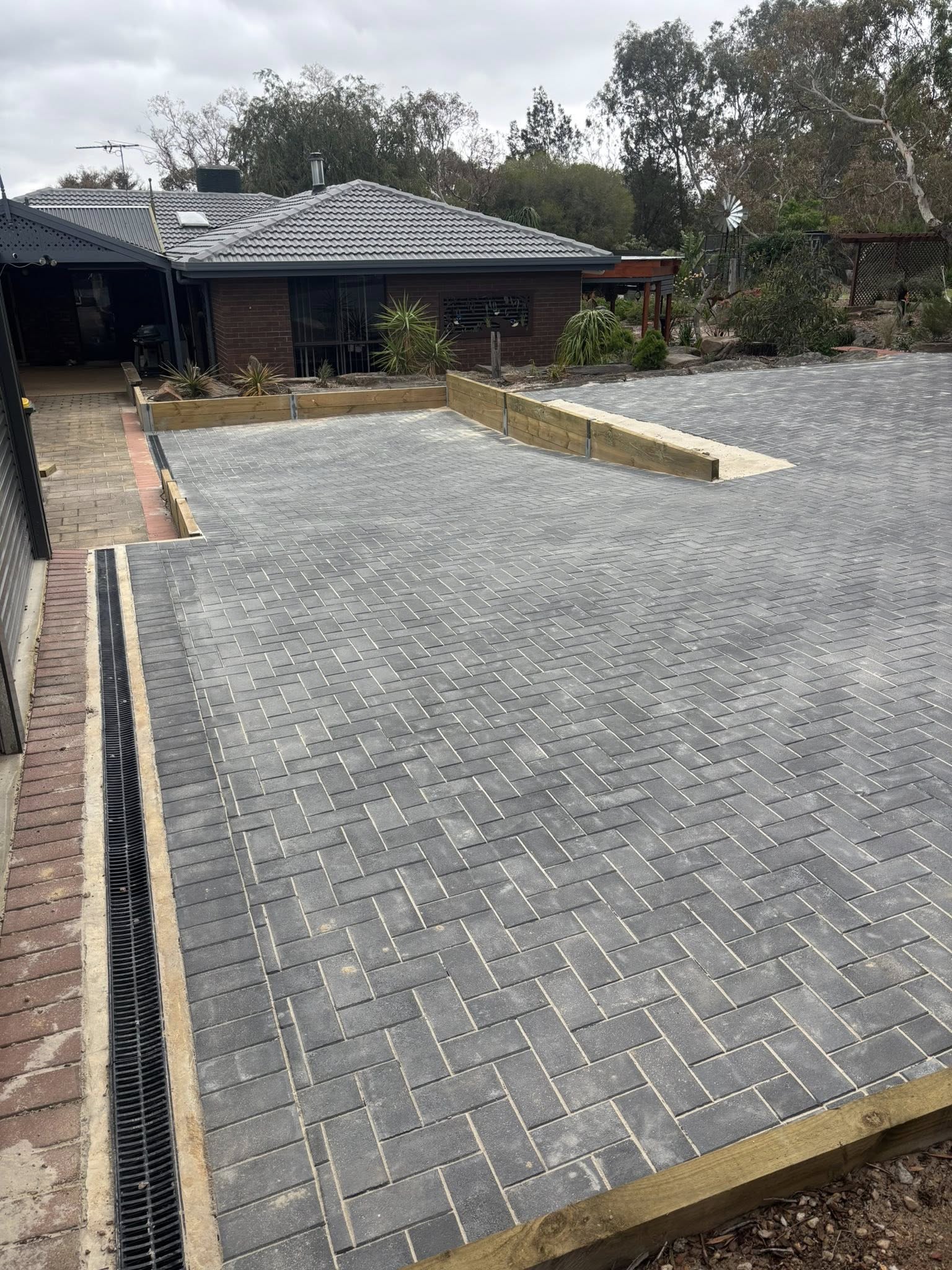Large grey brick driveway with retaining wall — residential paving