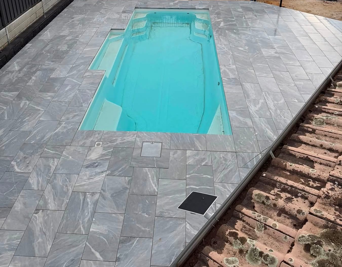 Elevated view of the full pool and new marble-look paving under a moody sky — May Paving