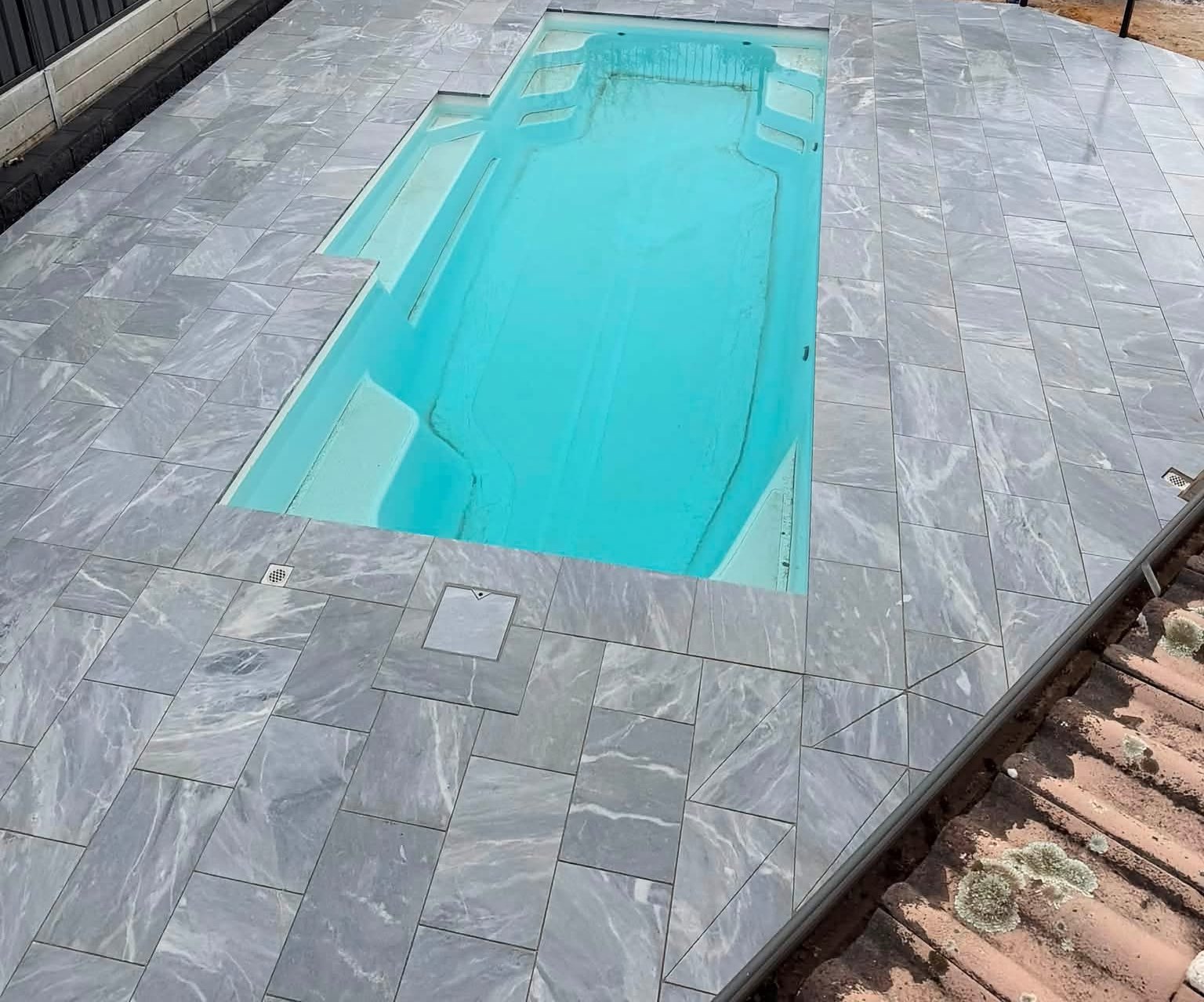 Aerial view of a finished fibreglass pool wrapped in marble-look grey pavers — pool surround by May Paving