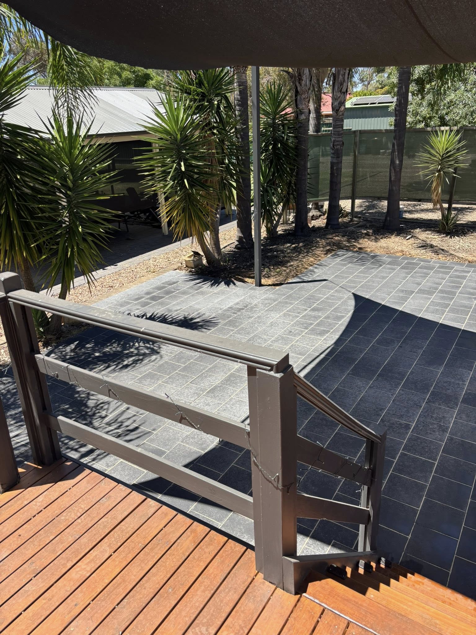 Dark slate pool surround viewed from composite timber deck — pool surround installation