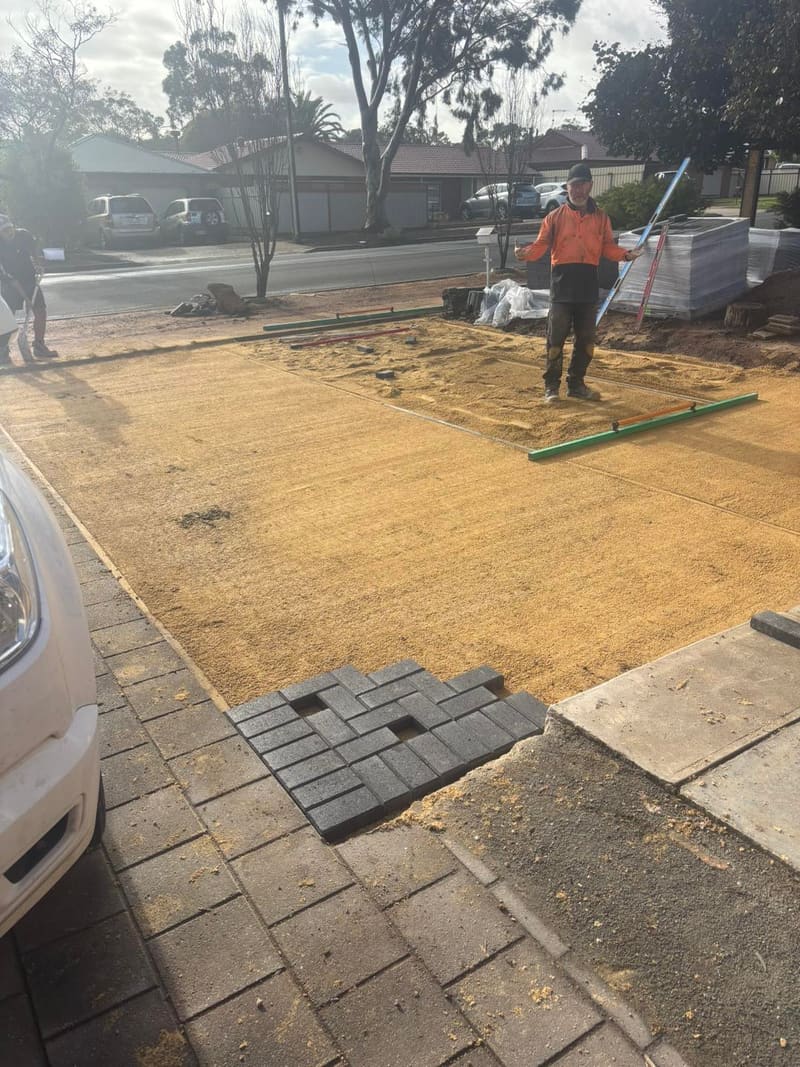 May Paving crew screeding the bedding sand before laying charcoal driveway pavers